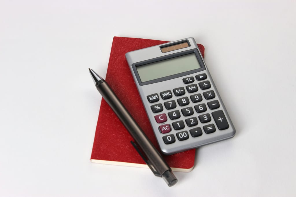 Calculatrice et stylo posés côte à côte sur un plan de travail clair